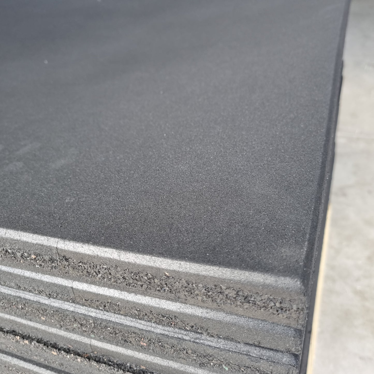 A close-up of a black rubber gym flooring tile showing its durability and slip-resistant texture