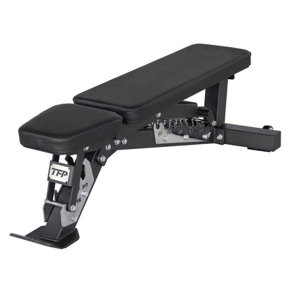 A black adjustable weight bench with a padded headrest and long inclined bench pad, shown on a plain white background. The frame is black metal with silver adjustment hardware, and the brand name TFP Fitness is visible on the leg support.