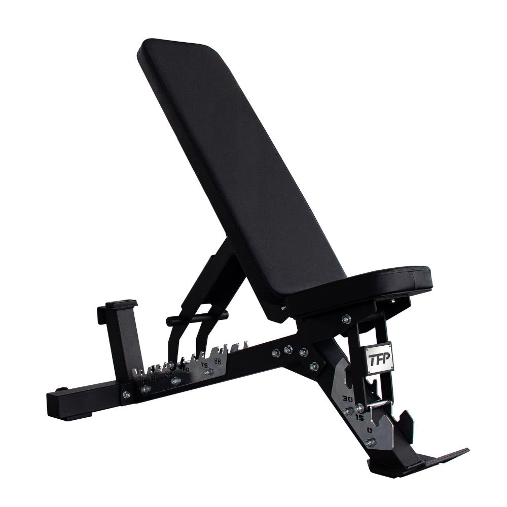 A black adjustable weight bench with a padded headrest and long inclined bench pad, shown on a plain white background. The frame is black metal with silver adjustment hardware, and the brand name TFP Fitness is visible on the leg support.
