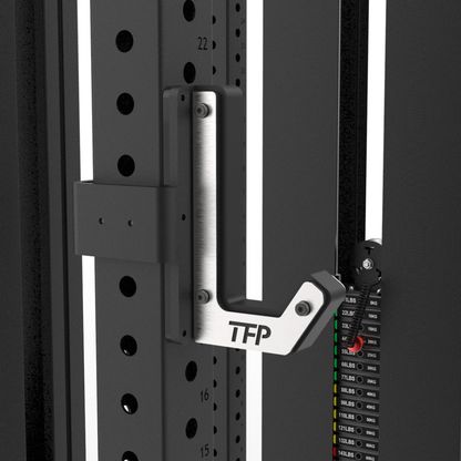 Close-up of a TFP pull-up bar attached to a black power rack with measurement markings and a weight stack.