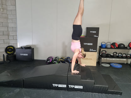 A woman performing a TFP Fitness Equipment handstand walk on Pro Series equipment in a gym.